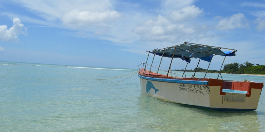 A boat on the shore of a beach with clear blue sky overhead in Andaman.