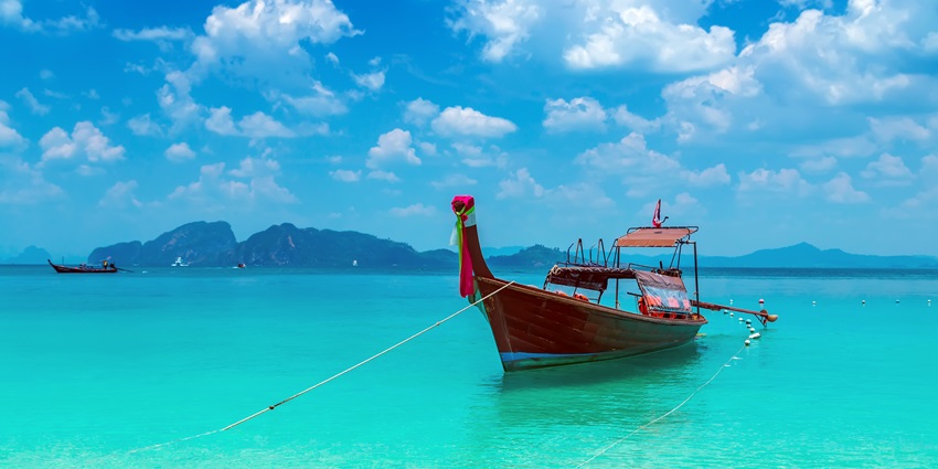 A boat in the middle of the still sea with white clouds overhead in Viper Island.