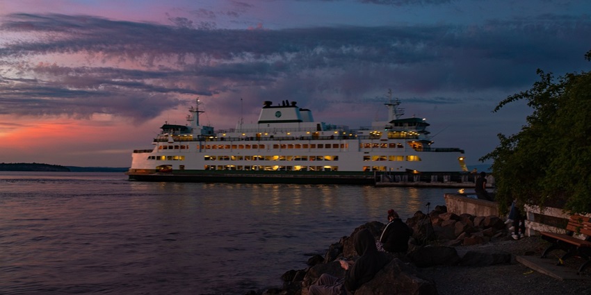 View of a ferry with the picturesque backdrop of a multi-coloured sky during sunset