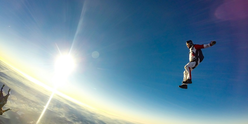 A picture of a man skydiving in India with the breathtaking view of sun in the backdrop.