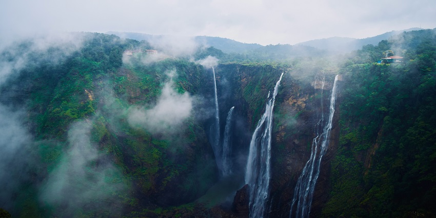 A serene view of Aanachadikuthu Waterfalls surrounded by emerald-green vegetation.