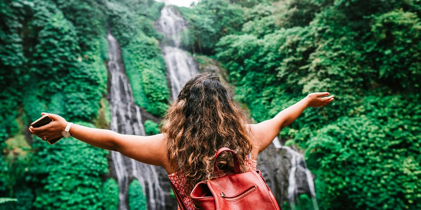Anonymous female traveller admiring amazing waterfall - enjoy trekking in the nature