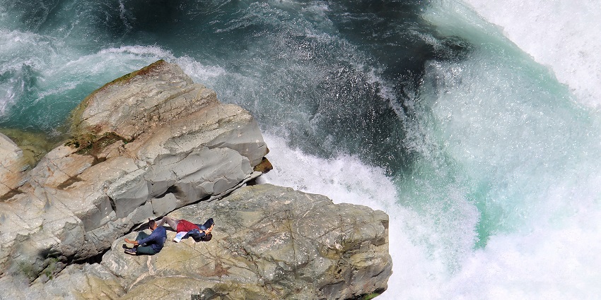 River flowing through Pahalagam one of the best places to visit An aerial shot of the Aharbal Waterfall with two visitors lying on the rock, resting.near Srinagar, India.