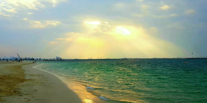A view of Al Mamzar Beach with turquoise waters and the reflection of the sun on it.