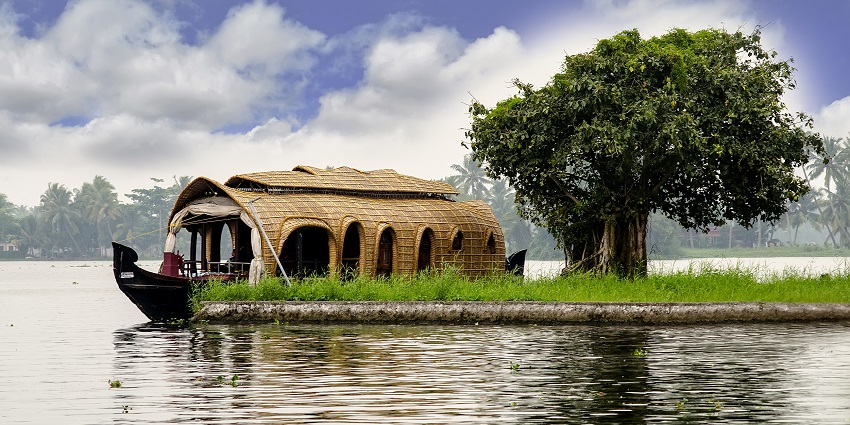 Boat gliding through the serene backwaters of Alappuzha, surrounded by lush scenery.