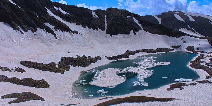 Alpather Lake in Gulmarg, Kashmir, surrounded by snow-capped peaks and lush meadows