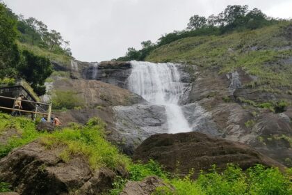 A mesmerising view of a waterfall in Kerala surrounded by lush greenery during the day.