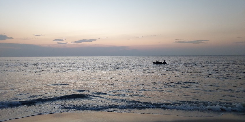 Enchanting view of the golden shores with a boat sailing through the waters of Arthunkal beach
