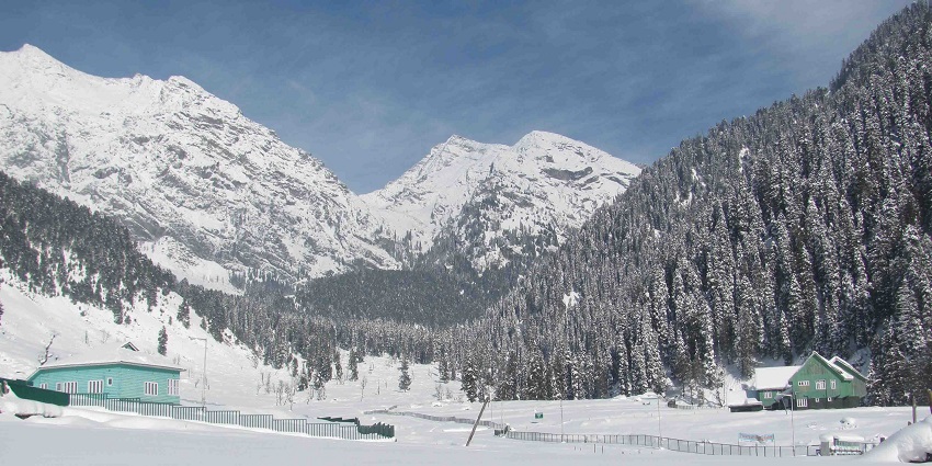A mesmerising view of snow-capped mountains, huts and trees in Aru Valley in Kashmir.