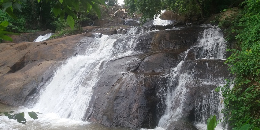 A captivating view of the famous Aruvikkuzhi Waterfalls cascading down the rocky cliffs