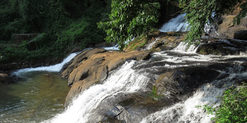 Image of Aruvikkuzhi Waterfalls surrounded by lush greenery and rocks around - Kottayam couple spot