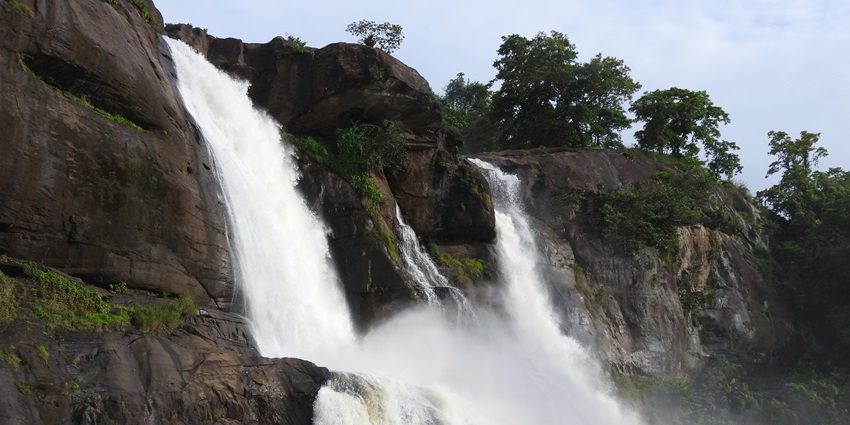 A picture of a beautiful waterfall with water cascading down a cliff, surrounded by greenery