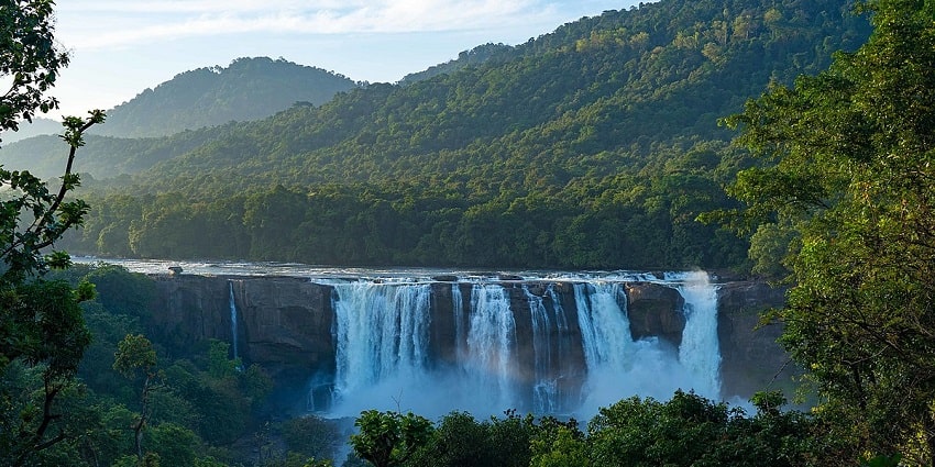 Water descending down the rocks of Athirappilly water falls surrounded by dense forests