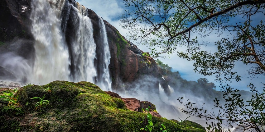 Enchanting view of water cascading down the rocks of Athirappilly falls amidst forested hills