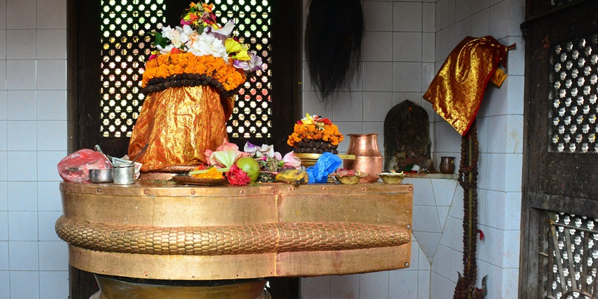 A picture of a Shiva Temple from the inside with a golden Shiva Linga present for worshipping