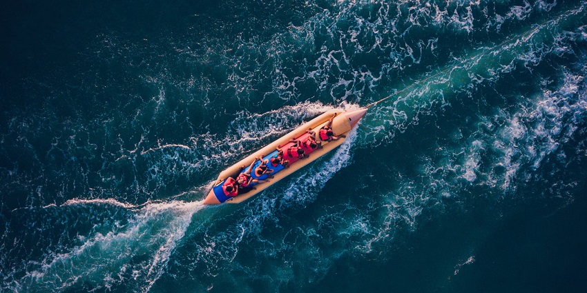 A group of people enjoying a banana boat ride in the sea with water splashing all around