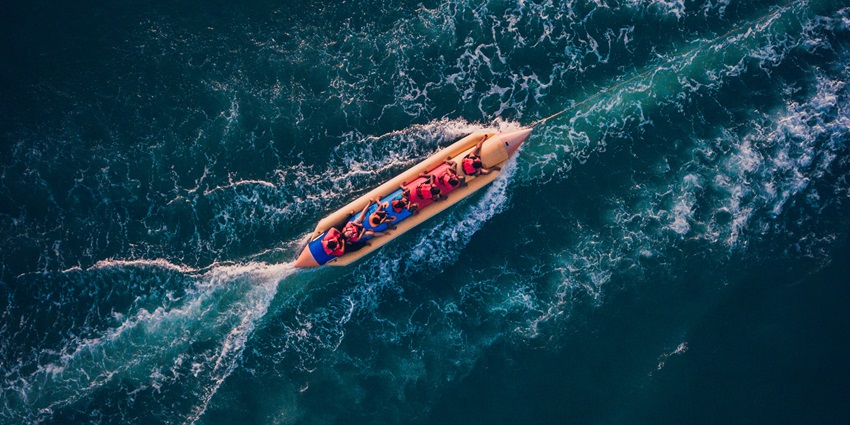 An eagle-eye view of the banana boat ride carrying people amidst the crystal-clear waters.