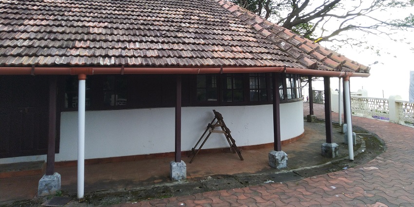 A picture of a traditional bungalow in Kerala with a garden area under a cover of lush greenery
