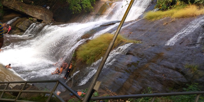 People enjoying a bath at Areekkal Waterfalls