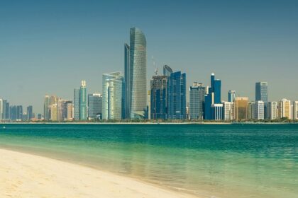 A view of the skyline of UAE with a turquoise body of water in front during the daytime.