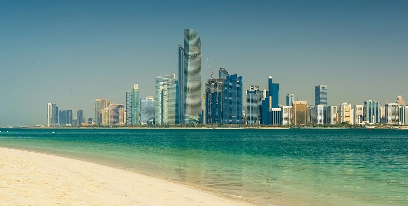 A view of the skyline of UAE with a turquoise body of water in front during the daytime.