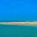 An iconic view of blue water and golden sand coming together on the beach