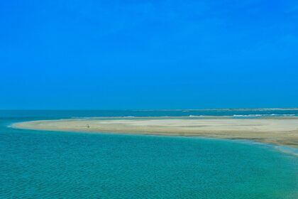 An iconic view of blue water and golden sand coming together on the beach