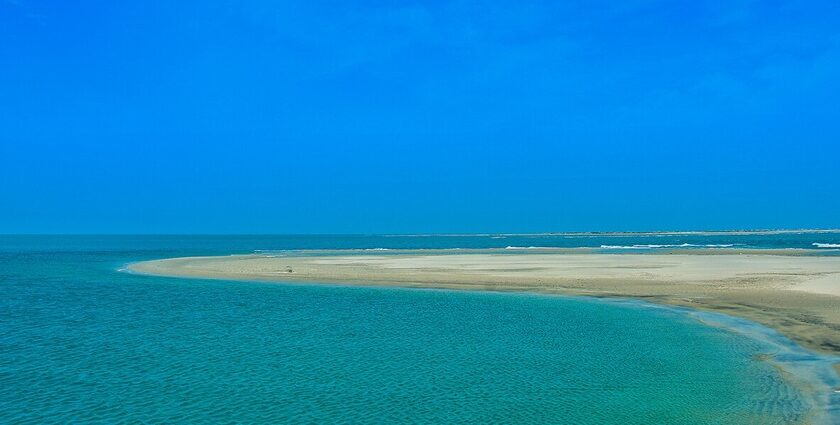 An iconic view of blue water and golden sand coming together on the beach