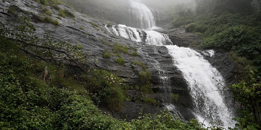 Sparkling water cascading down through the misty hills of Valara Waterfalls in Idukki