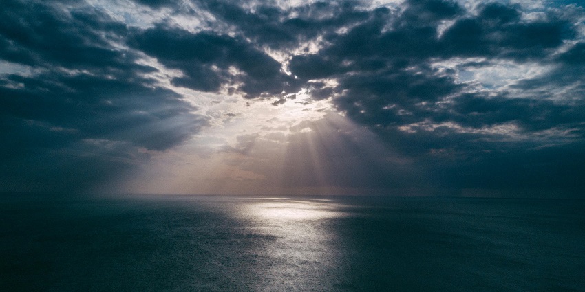 A fascinating view of a body of water during golden hour covered in dense grey clouds