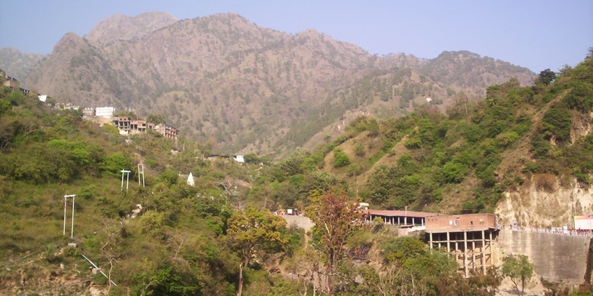 A mountainous landscape with rocky terrain and sparse vegetation with multiple peaks.