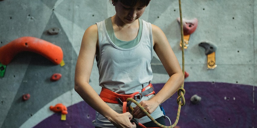A female climber clicked while getting ready with a belay for bouldering training
