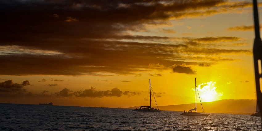 An aerial view of a Catamaran on a water body during the golden hour, a must-try activity.