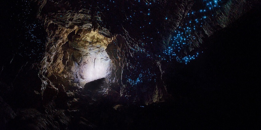A breathtaking view of the inside of a cave illuminating light at night.