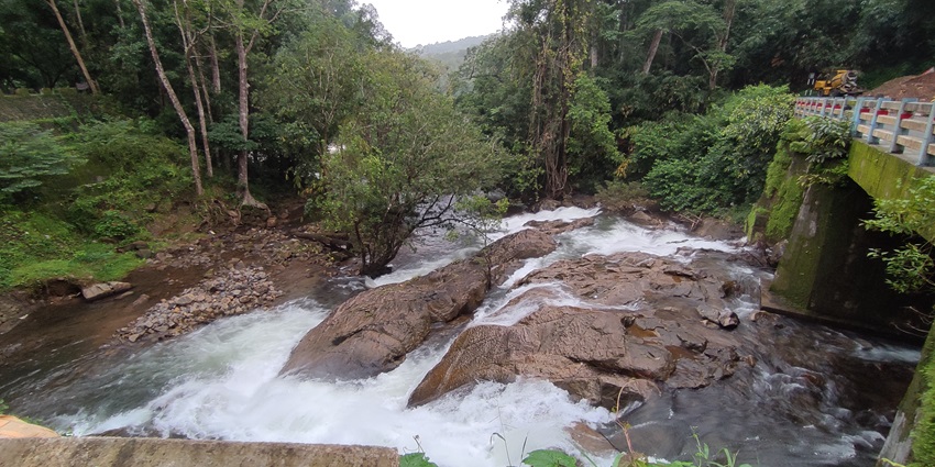 A picture of a waterfall from the top, with water flowing down the hill into a river