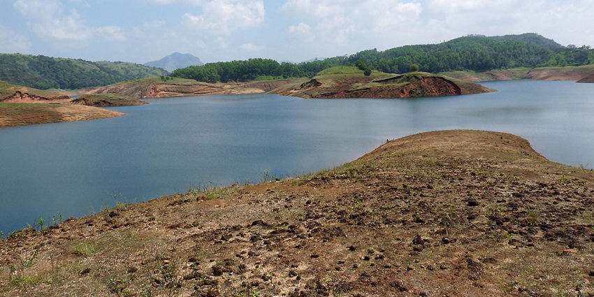 A breathtaking view of Cheruthoni Dam surrounded by lush greenery and mountains.