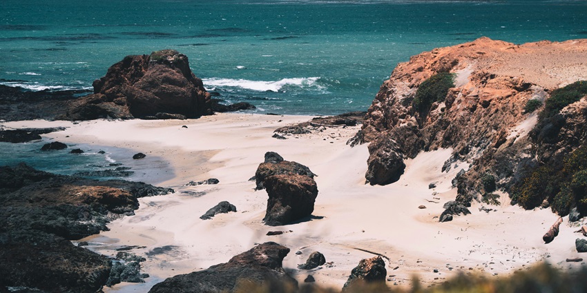 An aerial photograph of a beach with a rocky shore and turquoise waters, one of the best beaches near Palakkad