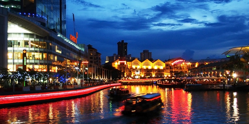 Nighttime riverfront at Clarke Quay, with illuminated buildings reflecting off the water—places to visit in singapore with family