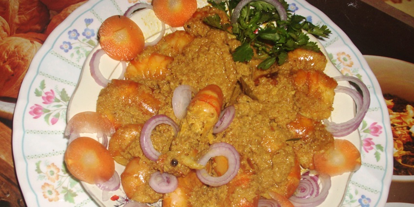 A delicious serving of coconut prawn curry with chopped onions and grated carrot slices