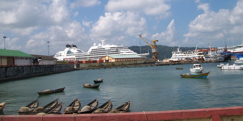 A picture of a harbour with various parked boats and a cruise ship in the background