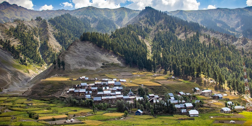 Picturesque view of lush green valleys in Jammu and Kashmir under scenic clouds and sky