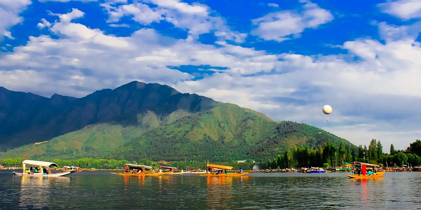 Snow-covered Dal Lake with Shikara boats gliding, capturing Srinagar's serene winter charm