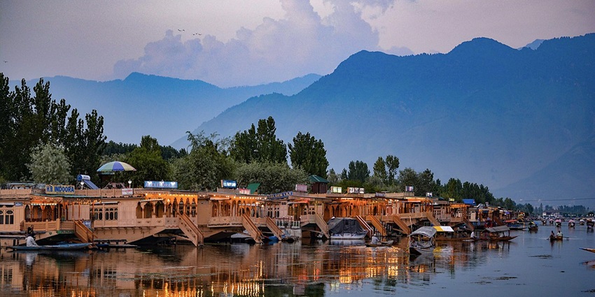 A scenic view of houseboats in Dal Lake in Srinagar with a backdrop of mountains