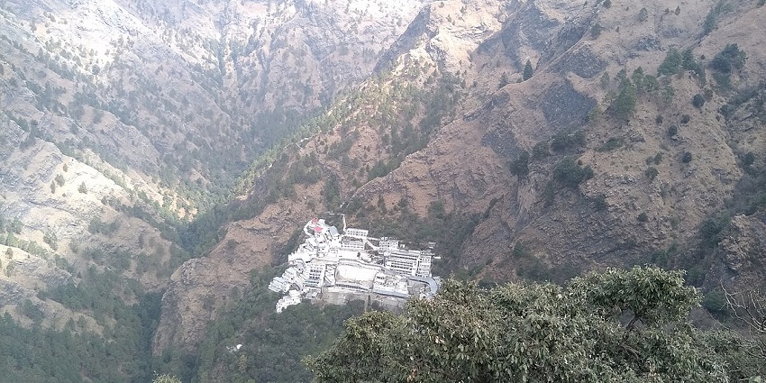 An aerial view of the Vaishno Devi Temple that is surrounded by rocky mountains and trees