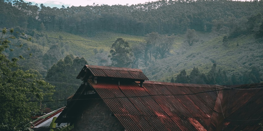 A beautiful view of a brown house nestled in lush greenery and clouds during the daytime.