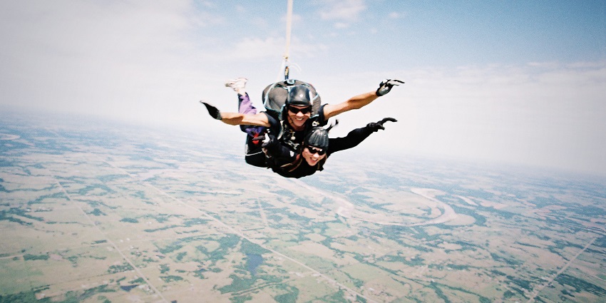 A picture showing two people skydiving amidst the clear skies with enchanting views.