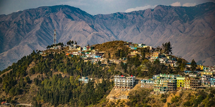 A view of houses on mountains amidst verdure and a scenic backdrop of cloudy sky