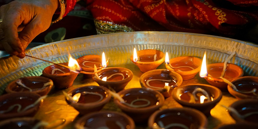 A picture of diyas being lit on the occasion of Diwali at night during the pooja.