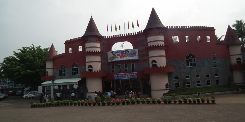 A picture of an amusement park from outside with castle-like walls and vibrant colours