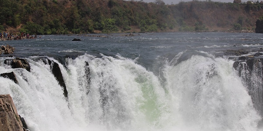 Spectacular Dudhsagar Waterfall, cascading down rocky terrain surrounded by forest.